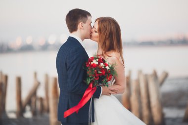 Güzel genç düğün çift, gelin ve damat arka plan denizde ahşap direklerin yakın poz