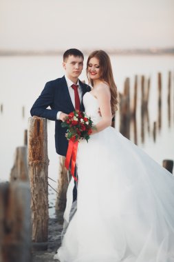 Güzel genç düğün çift, gelin ve damat arka plan denizde ahşap direklerin yakın poz