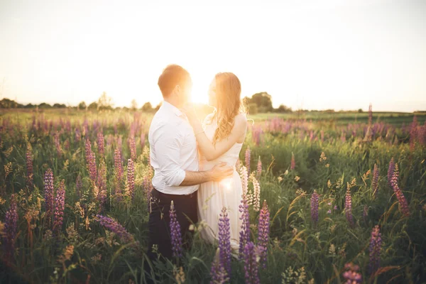 Bruden håller brudgummar hals medan han kysser henne i solnedgången strålar — Stockfoto