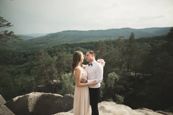 Nádherná nevěsta, ženich, líbání a objímání poblíž útesů s nádherným výhledem — Stock fotografie