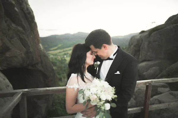 Ευτυχισμένος γάμος ζευγάρι φιλί και αγκαλιάζει κοντά σε ένα ψηλό βράχο — Φωτογραφία Αρχείου