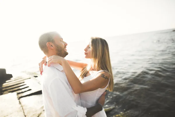 Casal amoroso romântico posando em pedras perto do mar, céu azul — Fotografia de Stock