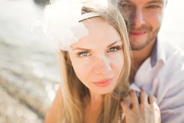 Matrimonio coppia baci e abbracci su rocce vicino al mare blu — Foto Stock