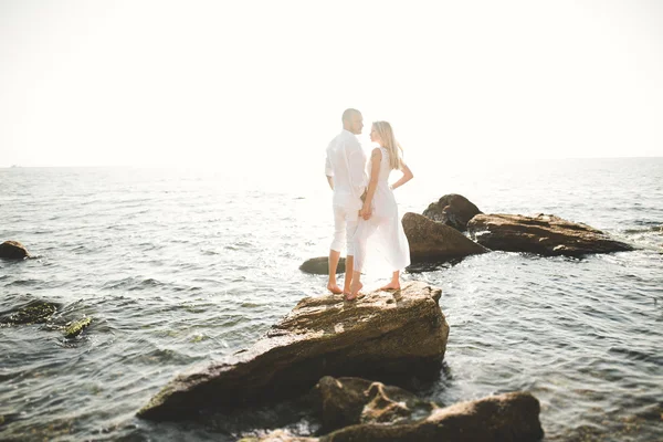 Romántica pareja amorosa posando sobre piedras cerca del mar, cielo azul —  Fotos de Stock
