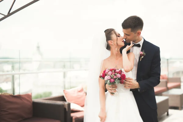 Prachtige paar, bruid en bruidegom poseren op balkon met backgrounf van de oude stad — Stockfoto