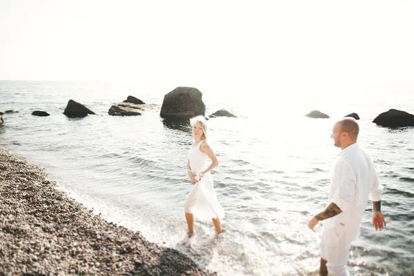 Casal amoroso romântico posando em pedras perto do mar, céu azul — Fotografia de Stock