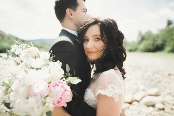 Close up portrait of couple against river and green trees. Beautiful young woman kissing handsome man outdoors — Stock Photo, Image