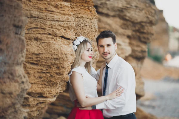 Romantisk kärleksfull par promenader på stranden med klippor och stenar — Stockfoto