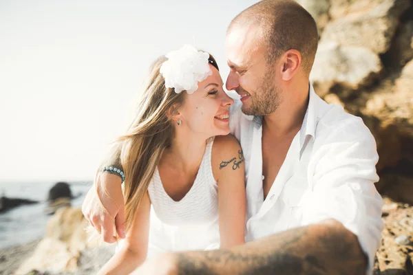 若いモデルのカップルがビーチで石のポーズ — ストック写真