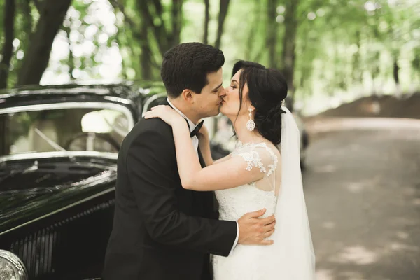 Hermosa pareja de boda posando cerca de espléndido coche retro — Foto de Stock