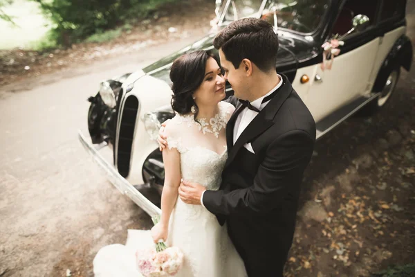 Stilvolles Hochzeitspaar, Braut, Bräutigam küssen und umarmen sich im Herbst in der Nähe von Retro-Autos — Stockfoto