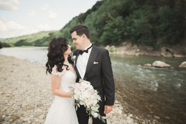 Zarif nazik şık damat ve gelin taşlarla Nehri yakınında. Evlilik çift aşık