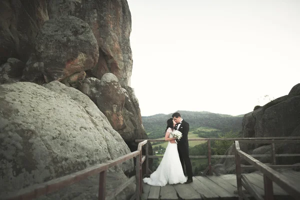 Verheugd huwelijksfeest paar zoenen en knuffelen in de buurt van een hoge klif — Stockfoto