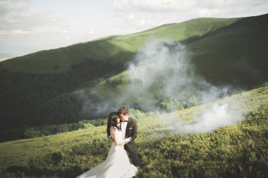 Harika bir gelin damada poz veriyor ve harika manzaralı dağlarda lüks bir tören yapıyor.