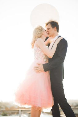 Çatıda mükemmel şehir manzaralı elele ve sarılma poz aşık genç bir çift. Güzel gün batımı