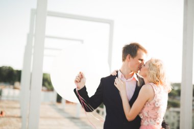 Çatıda mükemmel şehir manzaralı elele ve sarılma poz aşık genç bir çift. Güzel gün batımı