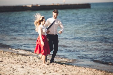 Genç mutlu çift holding birbirlerini etrafında gülümseyen Sahilde yürüyüş. Aşk hikayesi