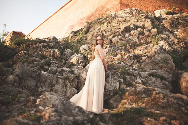 Jovem atraente em vestido longo em pé sobre as rochas — Fotografia de Stock