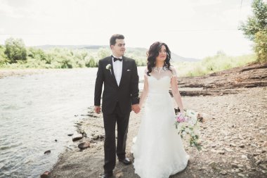 Gelin ve damat güzel düğün buket tutarak. Nehir kenarında poz