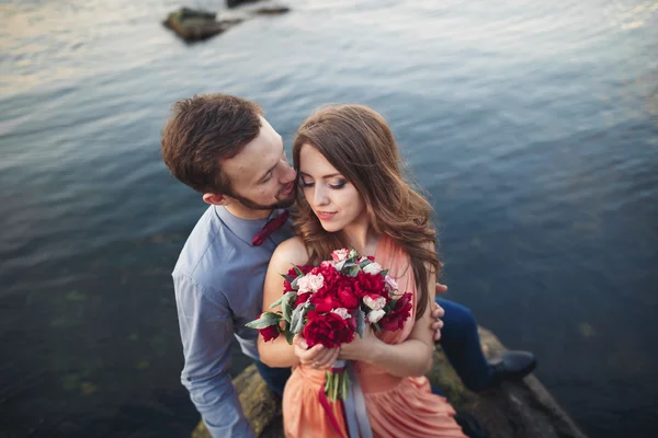 Svatební pár na velký kámen kolem modré moře — Stock fotografie