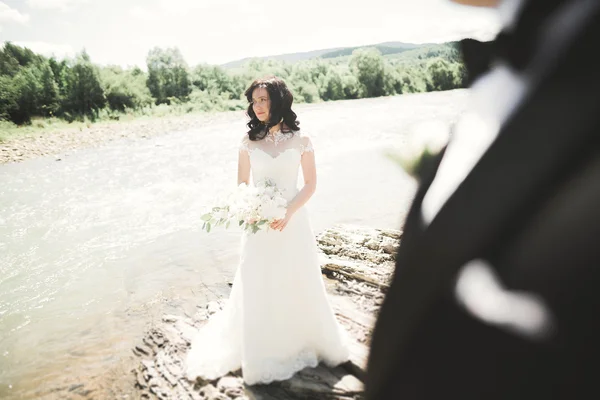 Élégant marié élégant doux et la mariée près de la rivière avec des pierres. Couple de mariage amoureux — Photo