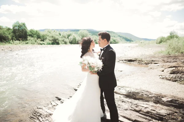 Mariée et marié tenant beau bouquet de mariage. Poser près de la rivière — Photo