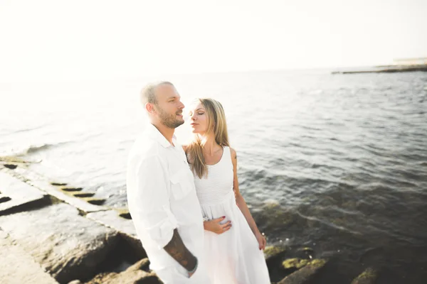 Boldog, csak házas fiatal esküvői pár ünnepli és szórakoztató gyönyörű tengerparton naplementekor — Stock Fotó