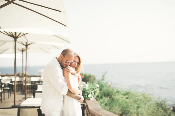 Matrimonio coppia baci e abbracci su rocce vicino al mare blu — Foto Stock