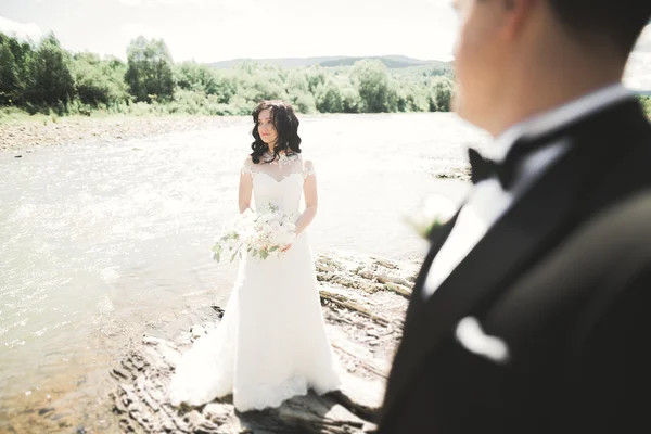 Наречений і наречений тримають гарний весільний букет. Позування біля річки — стокове фото