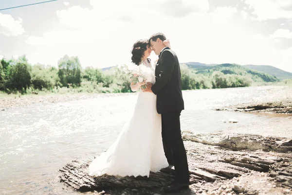 산기슭에서 돌로 키스를 하고 포옹을 하는 아름다운 부부 — 스톡 사진