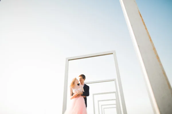 Jeune couple amoureux posant sur le toit avec vue parfaite sur la ville tenant la main et étreignant. Beau coucher de soleil — Photo