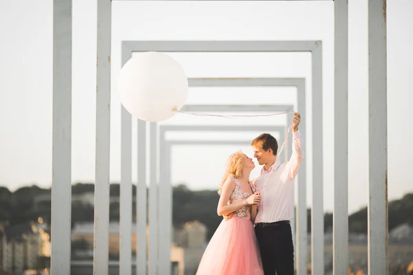 Retrato al aire libre bastante soleado de pareja joven y elegante mientras se besa en el techo con vista a la ciudad —  Fotos de Stock
