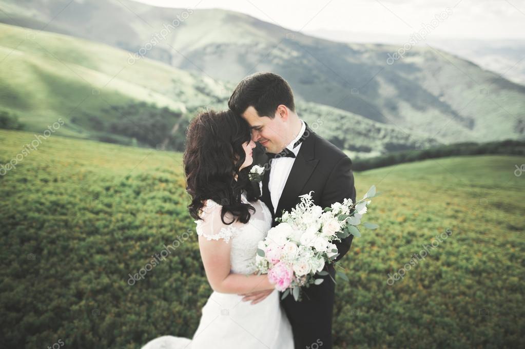 Beautifull wedding couple kissing and embracing near mountain with perfect view