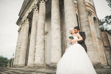 Güzel, romantik bir düğün. Yeni evliler. Eski kalenin yakınlarında sarılıyorlar.