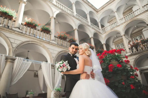 Krásný šťastný svatební pár, nevěsta s dlouhými bílými šaty pózuje v krásném městě — Stock fotografie