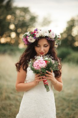 Gelin. Güzel sarışın kadın çiçek çelenk ve buket sıcak yaz gününde park