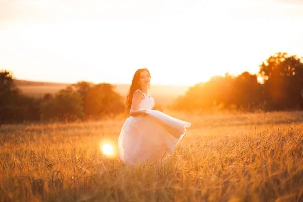 Feliz bela noiva jovem lá fora em um prado de verão no pôr do sol — Fotografia de Stock