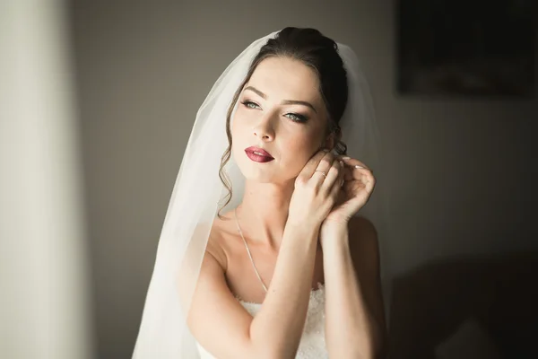 Hermosa novia joven con maquillaje y peinado en el dormitorio, mujer recién casada preparación final para la boda. Chica feliz esperando novio. Retrato de enfoque suave —  Fotos de Stock