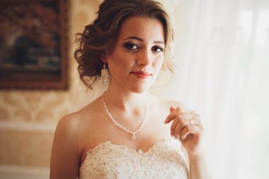 Beyaz elbiseli lüks gelin düğün törenine hazırlanırken poz veriyor.