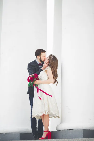 Beautiful couple, bride and groom posing near big white column — Stock Photo, Image