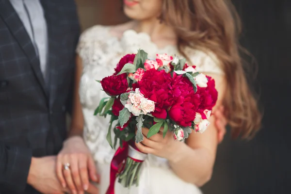 Весільна пара обіймає, наречена тримає букет квітів у руці, наречений обіймає — стокове фото