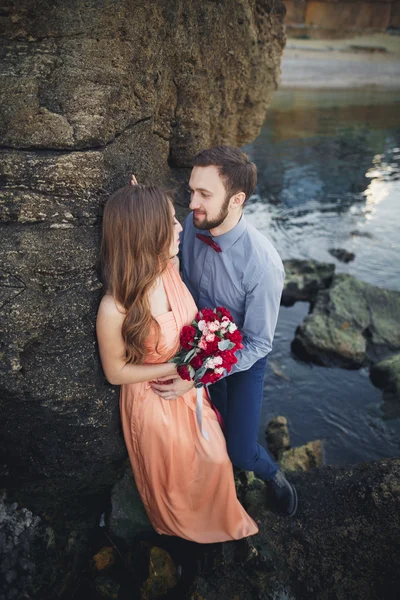 Matrimonio coppia seduta su una grande pietra intorno al mare blu — Foto Stock