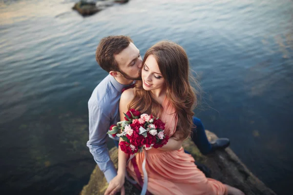 Svatební pár na velký kámen kolem modré moře — Stock fotografie