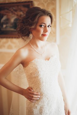 Beyaz elbiseli lüks gelin düğün törenine hazırlanırken poz veriyor.