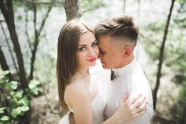 Düğün iki adam, öpüşme ve nehir, dağlar bir arka plan üzerinde sarılma gelin. Güzellik Portresi