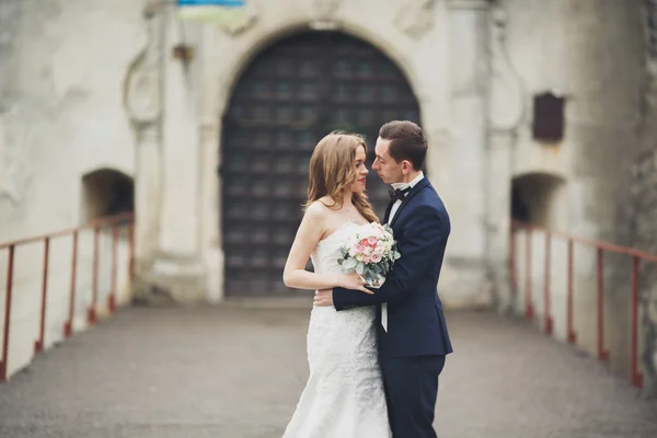 Feliz boda pareja abrazándose y sonriendo el uno al otro en el fondo viejo castillo — Foto de Stock