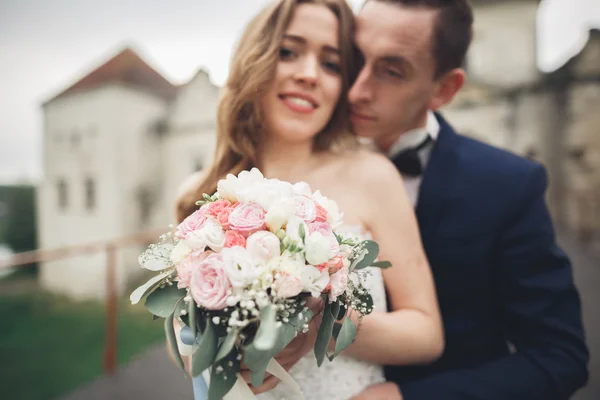 Appena sposati coppia di nozze posa e sposa tenendo in mano bouquet — Foto Stock