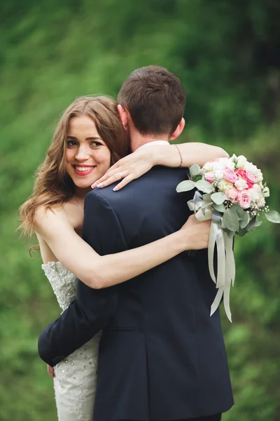 幸せな結婚式のカップルを抱き締めると城の背景の豪華な植物をお互いに笑みを浮かべて — ストック写真