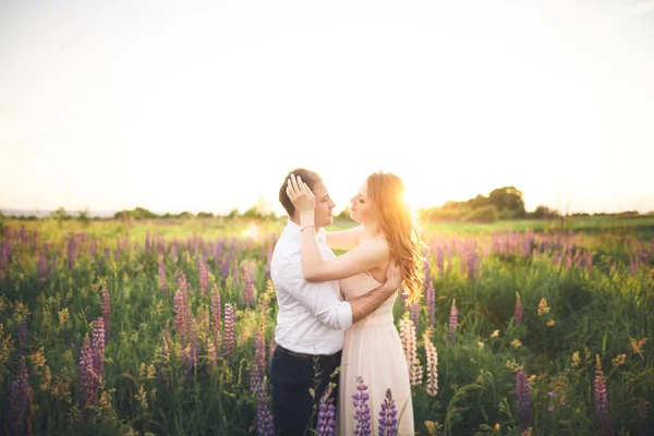 Emotionale schöne Braut umarmt frischvermählten Bräutigam von hinter Sonnenuntergang bei einem Feld Nahaufnahme — Stockfoto
