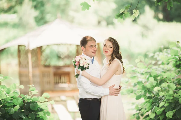 Bruiloft paar knuffelen en zoenen bij de brug — Stockfoto